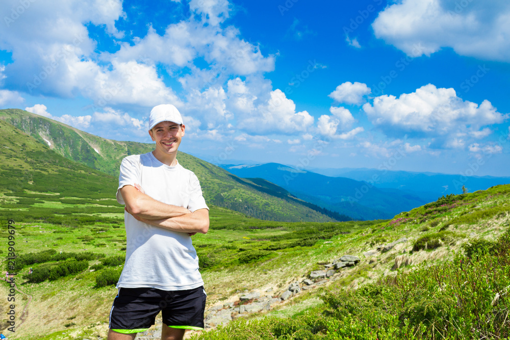 man hiker relaxing on top of hill and admiring beautiful mountain valley view in summer day man hiker relaxing on top of hill and admiring beautiful mountain valley view in summer day