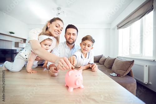 A smiling family saves money with a piggy bank. Happy family at the table in the room. photo