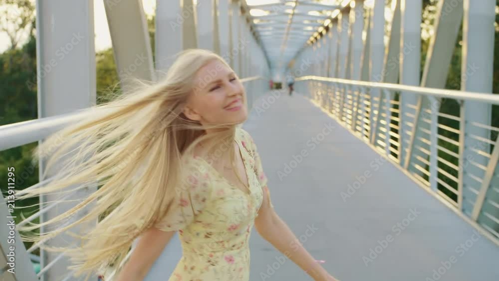 Woman looking back on bridge. Pretty blonde woman looking back at camera while running on bridge with wavy hair. Woman looking back on bridge. Pretty blonde woman looking back at camera while running on bridge with wavy hair.