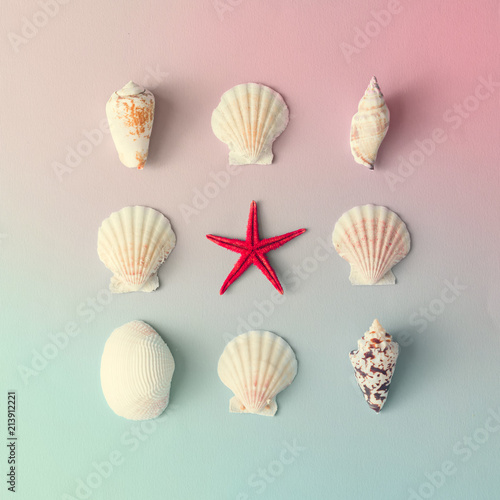 Creative seashell pattern on gradient pastel pink and blue background with red starfish. Summer flat lay.