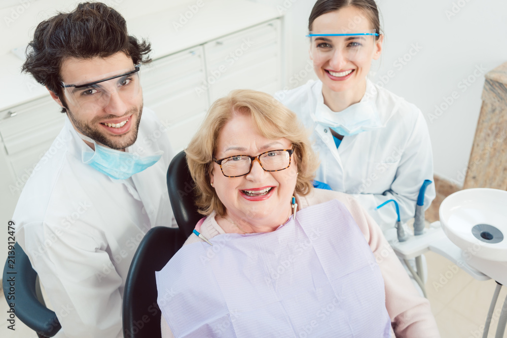 Dentists and patient in surgery looking at camera smiling Dentists and patient in surgery looking at camera smiling