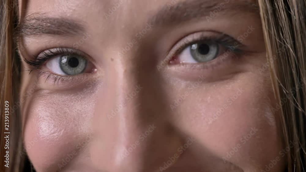 Eyes of young sencere girl is watching at camera, smiling, grey background Eyes of young sencere girl is watching at camera, smiling, grey background