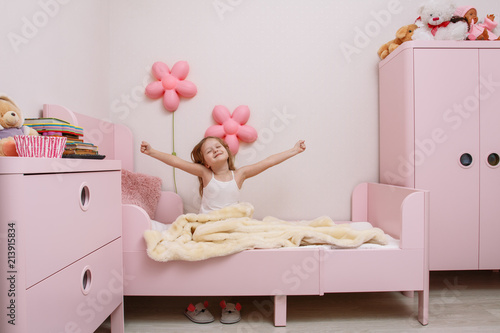 little girl wakes up in the morning in the children's bedroom