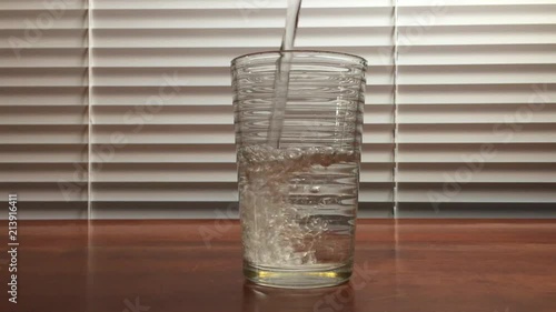 Pouring water into a glass and popping in two asprin photo
