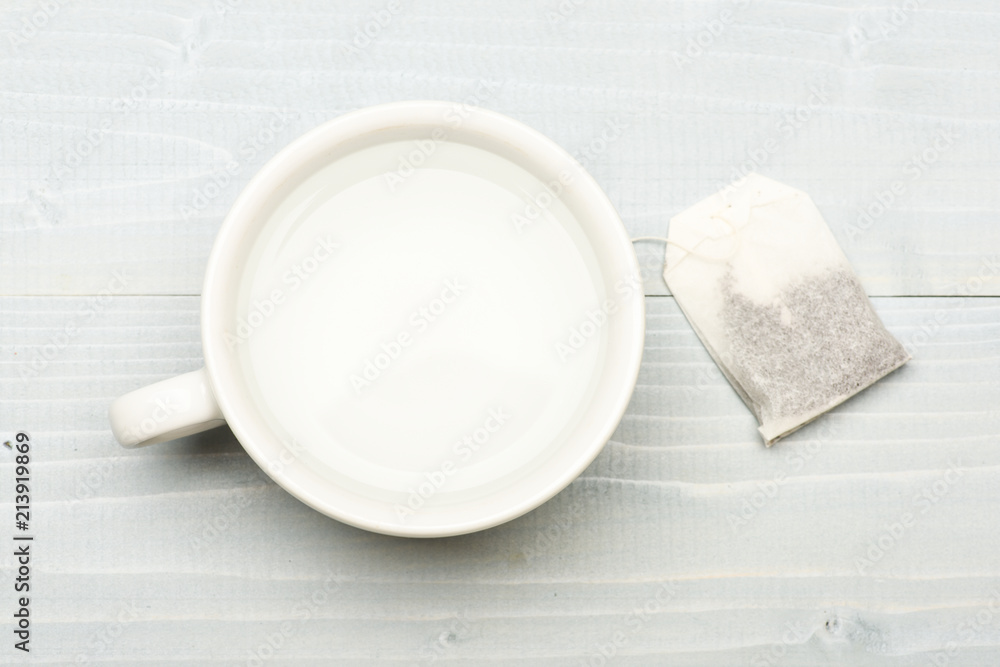 Mug filled with boiling water and teabag on white background. Process ...