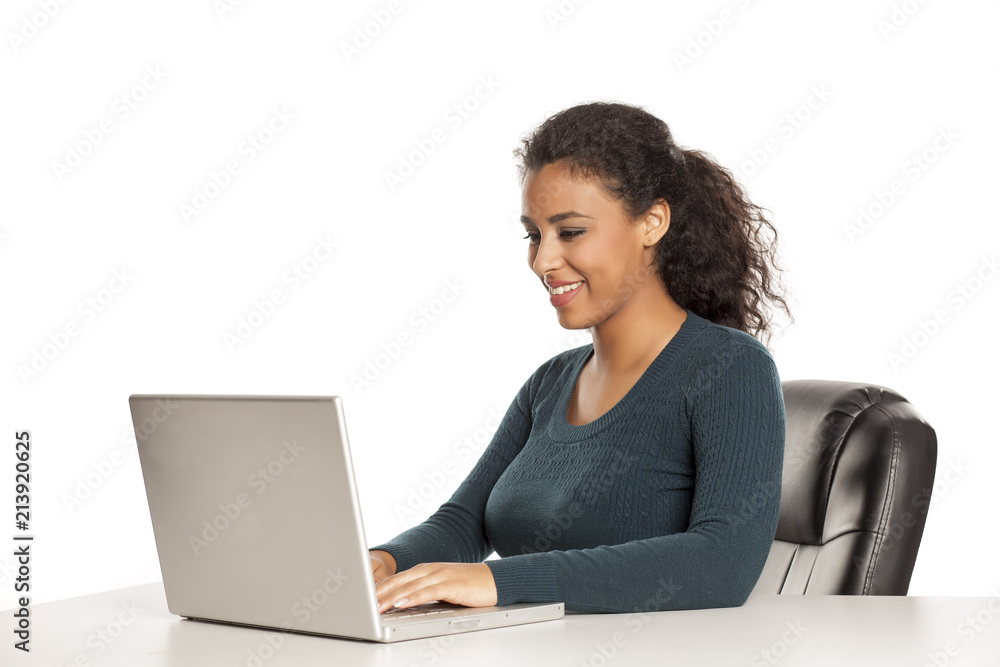 Smiling and positive happy young african-american woman with beautiful face using laptop computer, working project at desk on white background Smiling and positive happy young african-american woman with beautiful face using laptop computer, working project at desk on white background