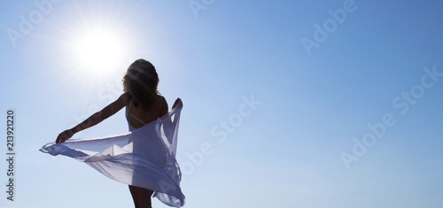beautiful girl in front of the sun against the blue sky