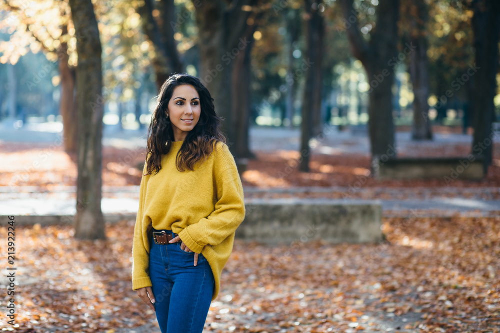 Cheerful casual woman walking at city park in autumn. Fall season fashion. Cheerful casual woman walking at city park in autumn. Fall season fashion.