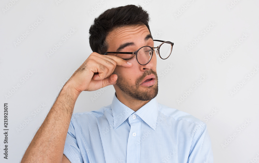 Closeup image of handsome bored sleepy unshaven male after long overwork in office, wants to sleep, wearing round spectacles and blue shirt isolated on white studio background with copy space. Closeup image of handsome bored sleepy unshaven male after long overwork in office, wants to sleep, wearing round spectacles and blue shirt isolated on white studio background with copy space.