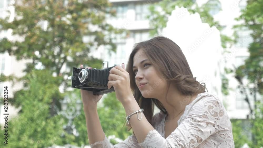 Beautiful young girl with long hair, taking pictures of sights on a vintage phone Beautiful young girl with long hair, taking pictures of sights on a vintage phone