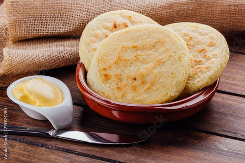 Plate with arepas and butter aside on a rustic wooden background