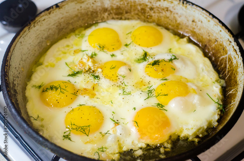 fried eggs in the home kitchen, omelette with herbs and spices in a frying pan.