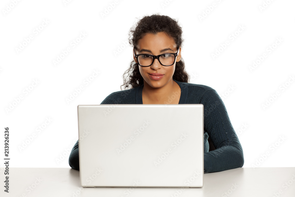 Smiling and positive young african-american woman with beautiful face using laptop computer, working project at desk on white background Smiling and positive young african-american woman with beautiful face using laptop computer, working project at desk on white background