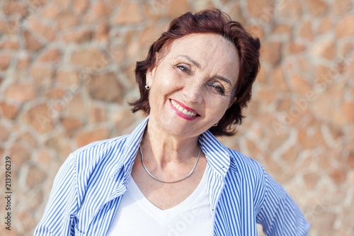 Portrait of a mature attractive  50-60 years stylish woman retired and outdoors on a summer sunny day, head shot