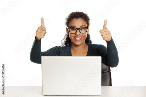 Smiling and positive happy young african-american woman with beautiful face using laptop computer, working project at desk on white background and showing thumbs up