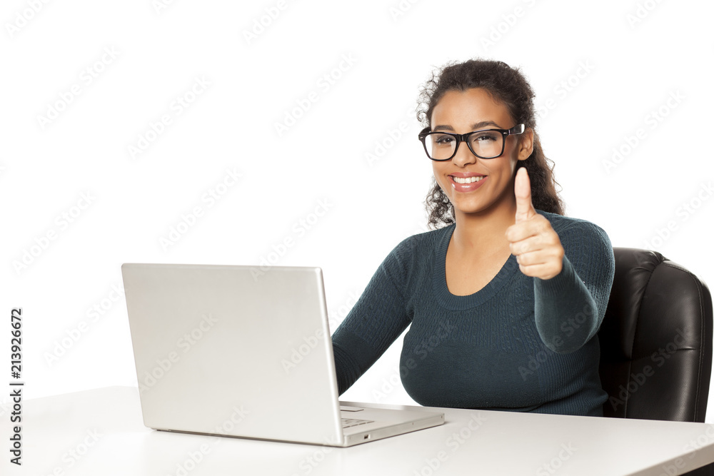 Smiling and positive happy young african-american woman with beautiful face using laptop computer, working project at desk on white background and showing thumbs up Smiling and positive happy young african-american woman with beautiful face using laptop computer, working project at desk on white background and showing thumbs up