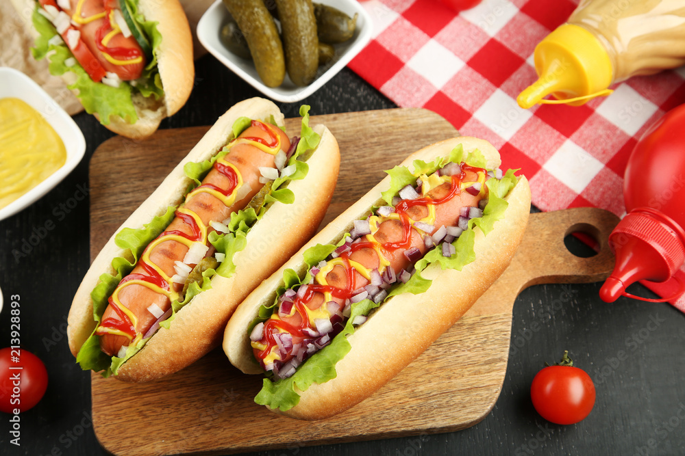 Hot dogs with ketchup, mustard and vegetables on wooden table Hot dogs with ketchup, mustard and vegetables on wooden table