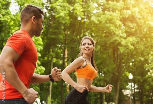 Athletic couple running together in park