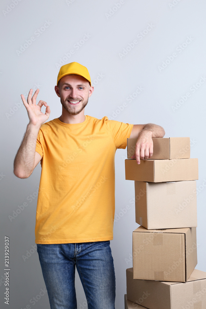 Delivery man with cardboard boxes on grey background Delivery man with cardboard boxes on grey background