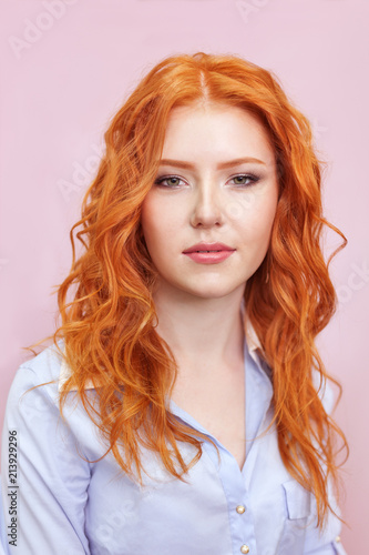 Portrait of beautiful red-haired girl on pink background