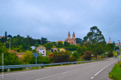 Road to Cobreces and San Pedro ad Vincula church  Iglesia de San Pedro ad Vincula  with houses around at the background  in Cobreces  Cantabria  Spain