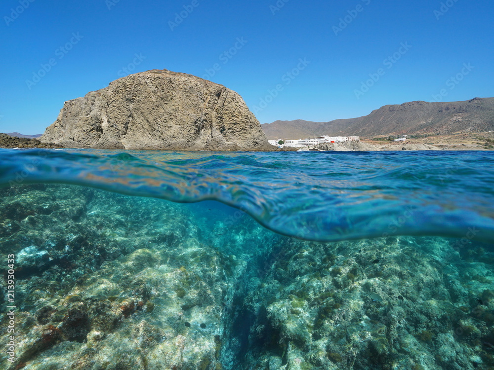 Rock formation on the seashore with the village La Isleta del Moro and rocks underwater, split view above and below water surface, Mediterranean sea, Cabo de Gata-Níjar, Almeria, Andalusia, Spain