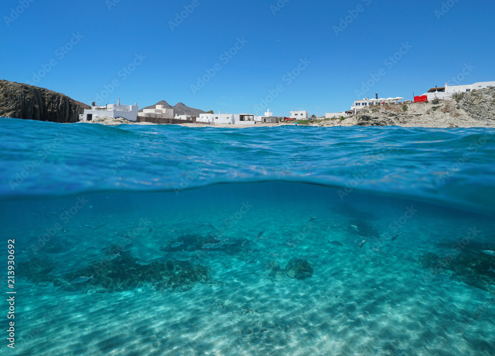 The picturesque village La Isleta del Moro on the seashore with fish and sand underwater, split view above and below water surface, Mediterranean sea, Cabo de Gata-Níjar, Almeria, Andalusia, Spain