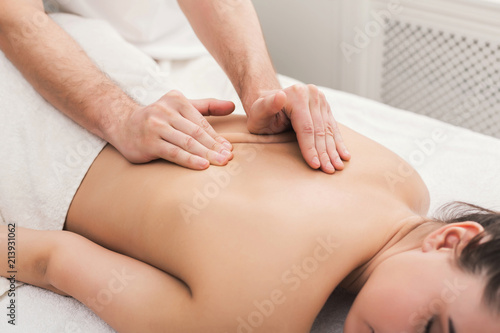 Closeup of hands massaging female shoulders and back