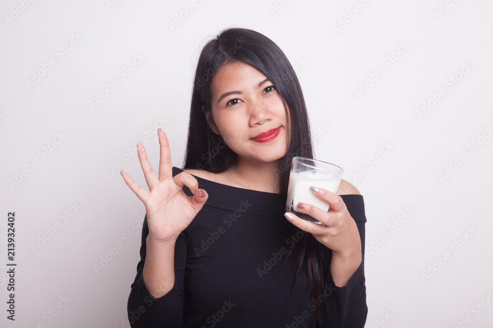 Healthy Asian woman drinking a glass of milk show OK sign.