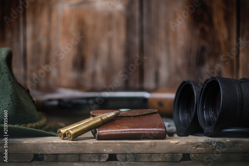 Professional hunters equipment for hunting. Detail on the ammunition. Wooden black background with rifle, hat, and other equipment for hunting. 
