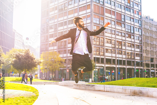 Canvastavla Young handsome contemporary business man jumping outdoor in city back light - su