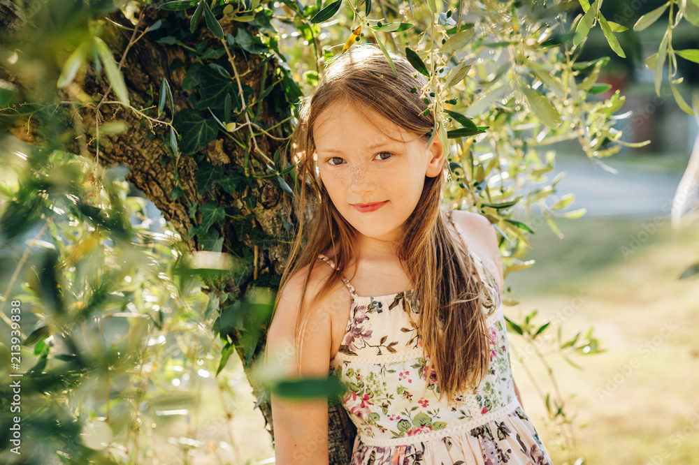 Outdoor portrait of adorable little girl wearing light dress, playing next to olive tree, summer vacation in Tuscany, Italy Outdoor portrait of adorable little girl wearing light dress, playing next to olive tree, summer vacation in Tuscany, Italy