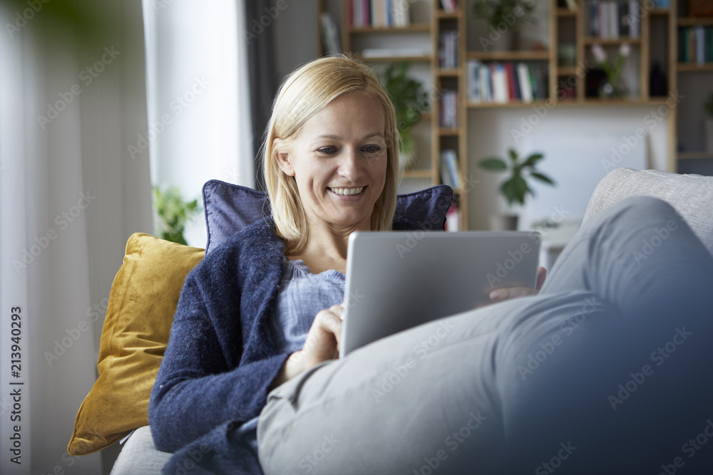Woman using digital tablet, relaxing on couch Woman using digital tablet, relaxing on couch