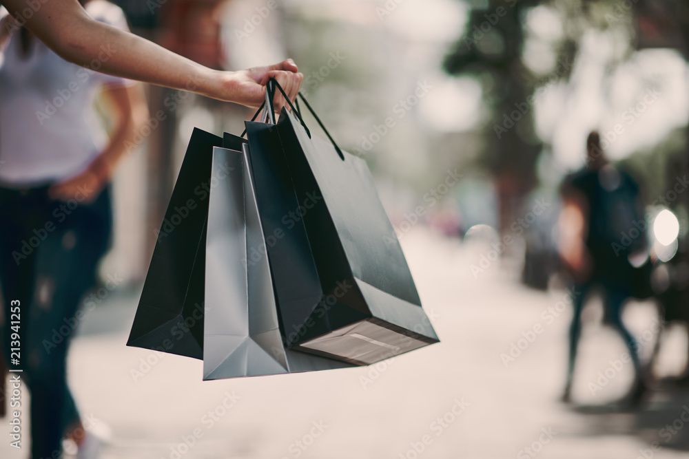 Close up of woman`s hand holding shopping bags while walking on the street.  Stock Photo | Adobe Stock