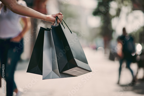 Close up of woman`s hand holding shopping bags while walking on the street. photo