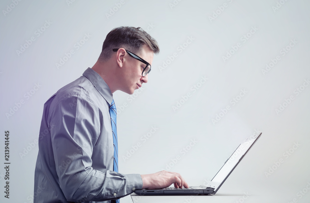Man in glasses, shirt and tie is working on laptop, side view. Man in glasses, shirt and tie is working on laptop, side view.