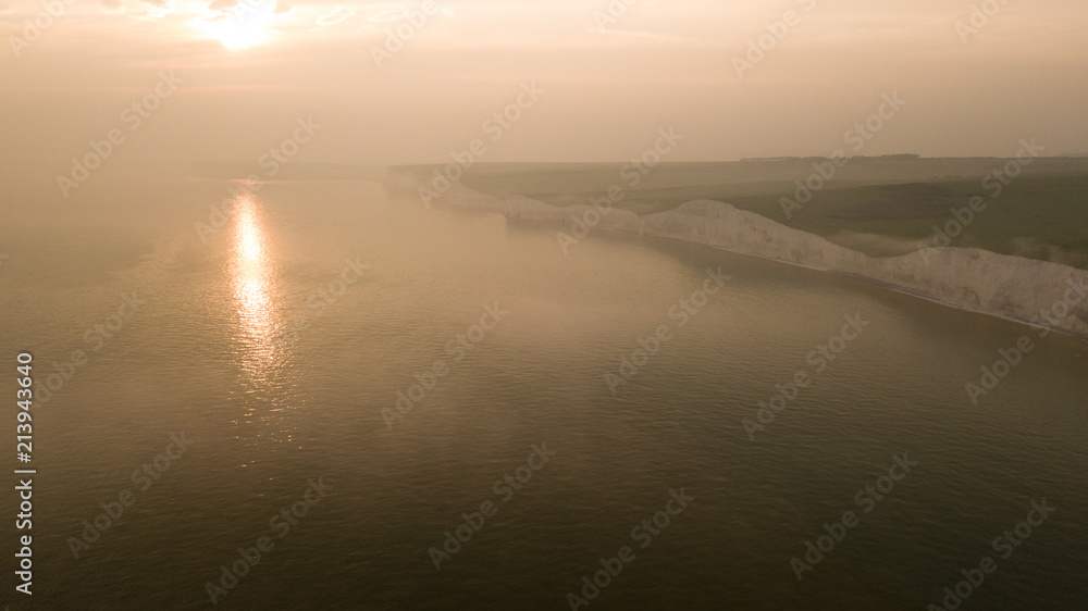 Aerial of foggy Seven Sisters Cliffs coast landscape in England at sunset