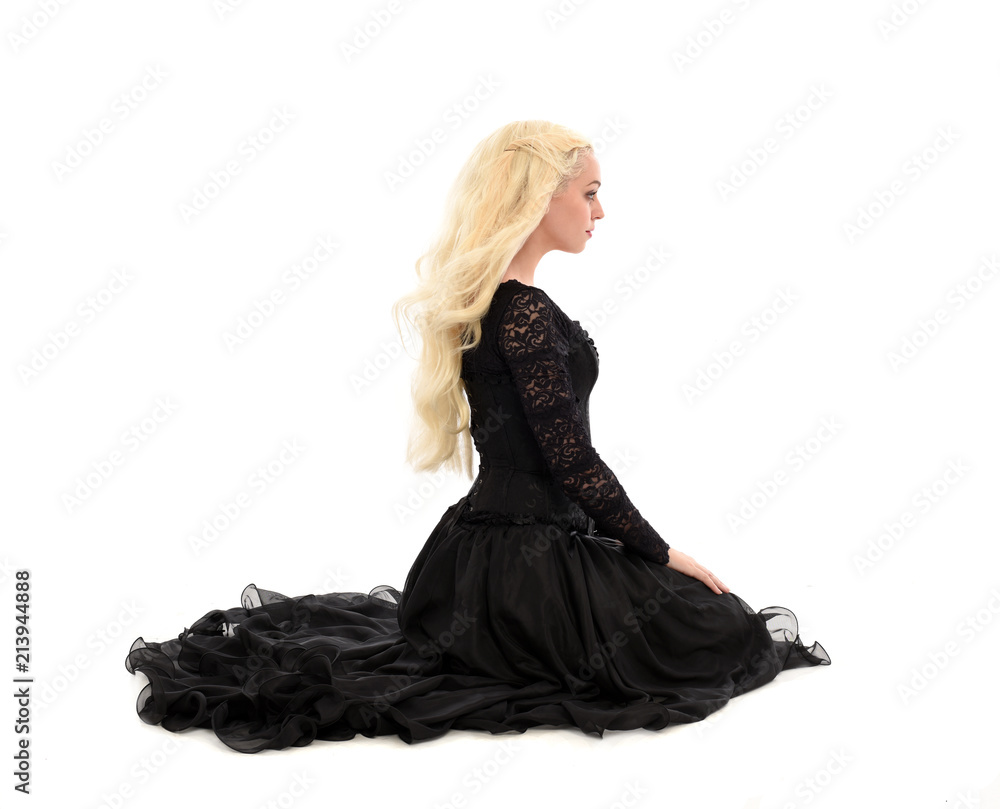 Naklejka premium full length portrait of blonde girl wearing corset and long black gown. isolated on white studio background,