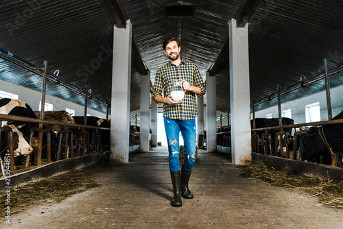 handsome farmer walking in stable with jug of milk