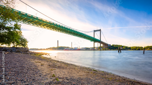 The landmark of gothenburg älvsborgsbron bridge connecting hisingen to city. The setting sun creating golden glow over green metalic bridge