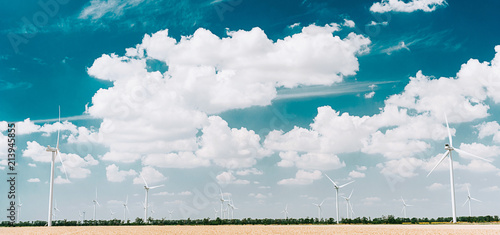 wind power station against the sky with clouds and a wheat field in the foreground