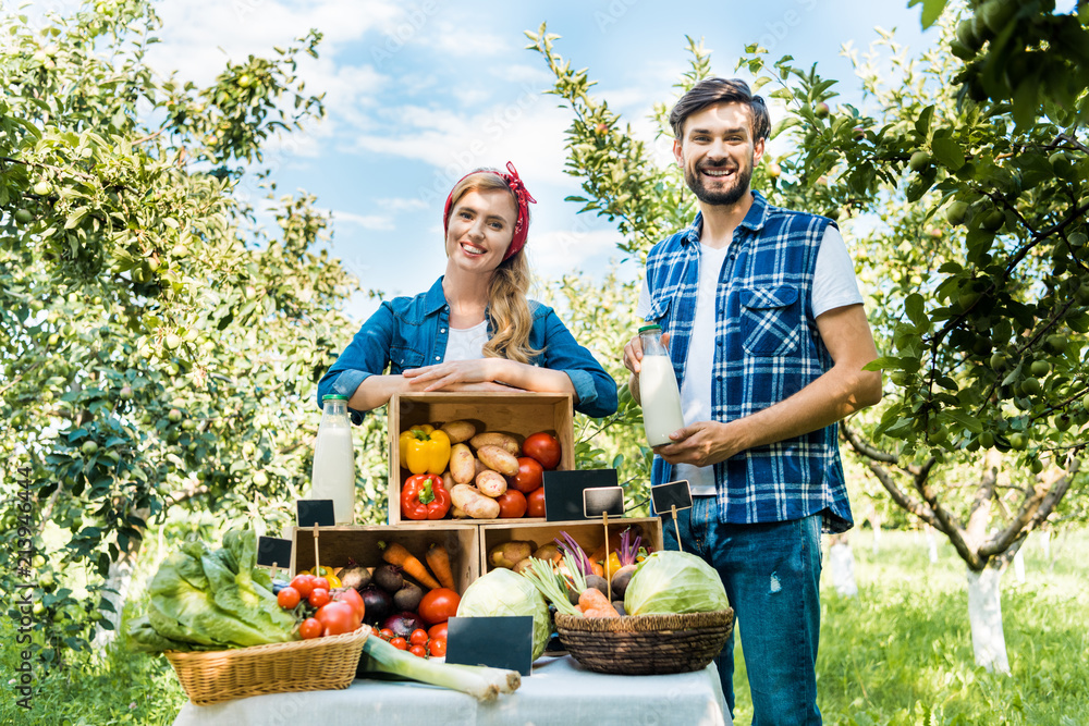 Obraz premium Smiling couple of farmers looking at camera at farmer market