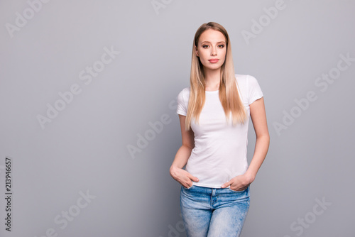 Close up portrait of confident young blonde woman stand and looking at camera isolated on gray background with copy space for text