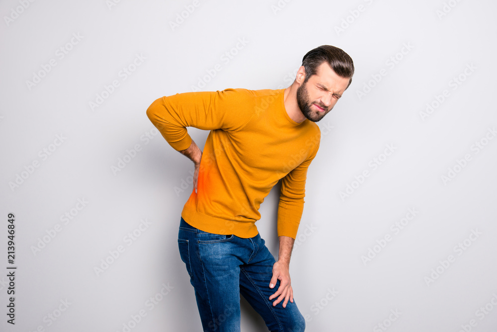 Lifestyle people person concept. Profile side view portrait of sad upset grimacing entrepreneur feeling pain in back isolated on gray background. Place of pain is marked with red spot Lifestyle people person concept. Profile side view portrait of sad upset grimacing entrepreneur feeling pain in back isolated on gray background. Place of pain is marked with red spot