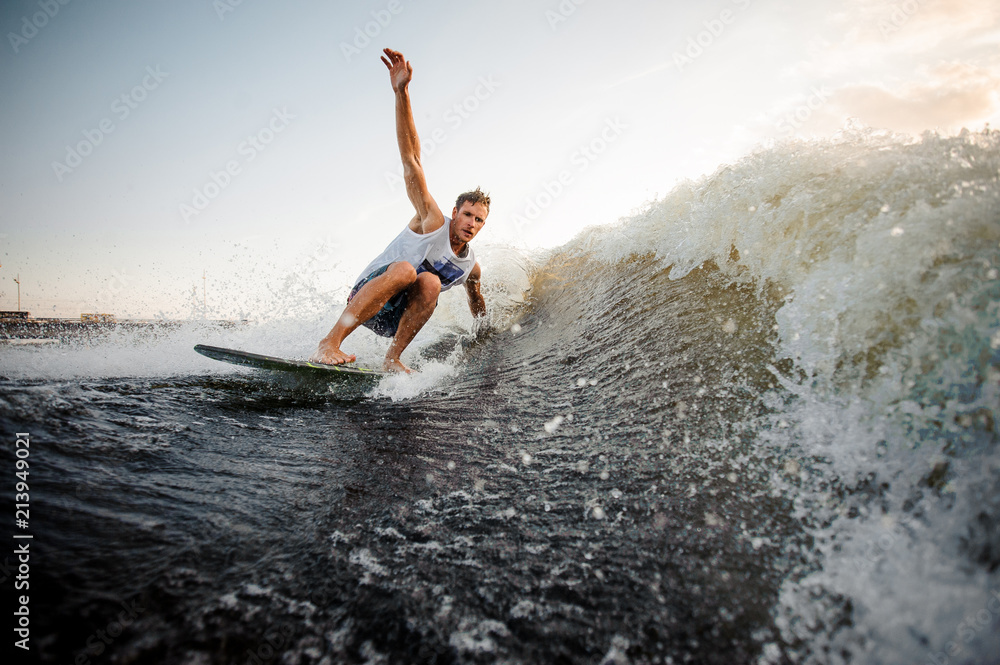 Young wakesurfer riding down the river waves