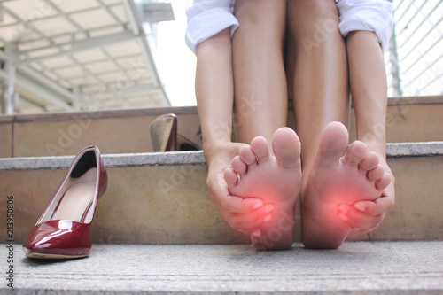 Close-up of young woman feeling pain in her foot on stair, Have ankle pain, Health concept