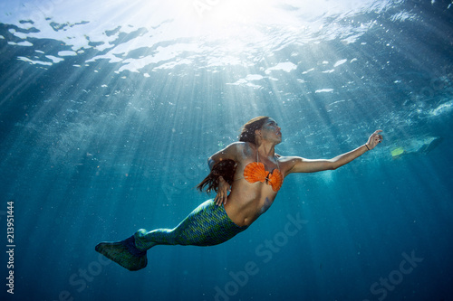 Mermaid swimming underwater in the deep blue sea