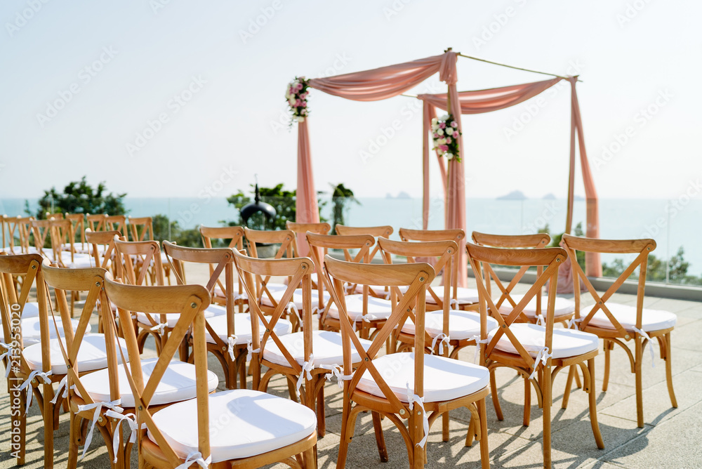 Wedding venue setting on the hill with wooden folding lawn chairs with panoramic ocean background view