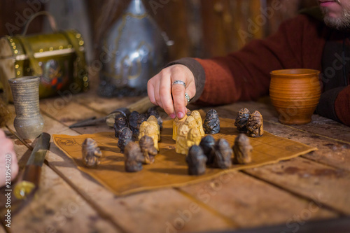 Close up shot - two men in russian ethnic suit playing medieval popular strategy board game - tafl. Folk, competition and traditional concept