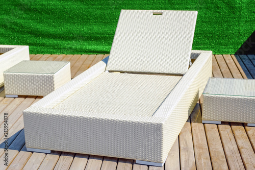 Rattan table and chaise longues near modern swimming pool, closeup photo